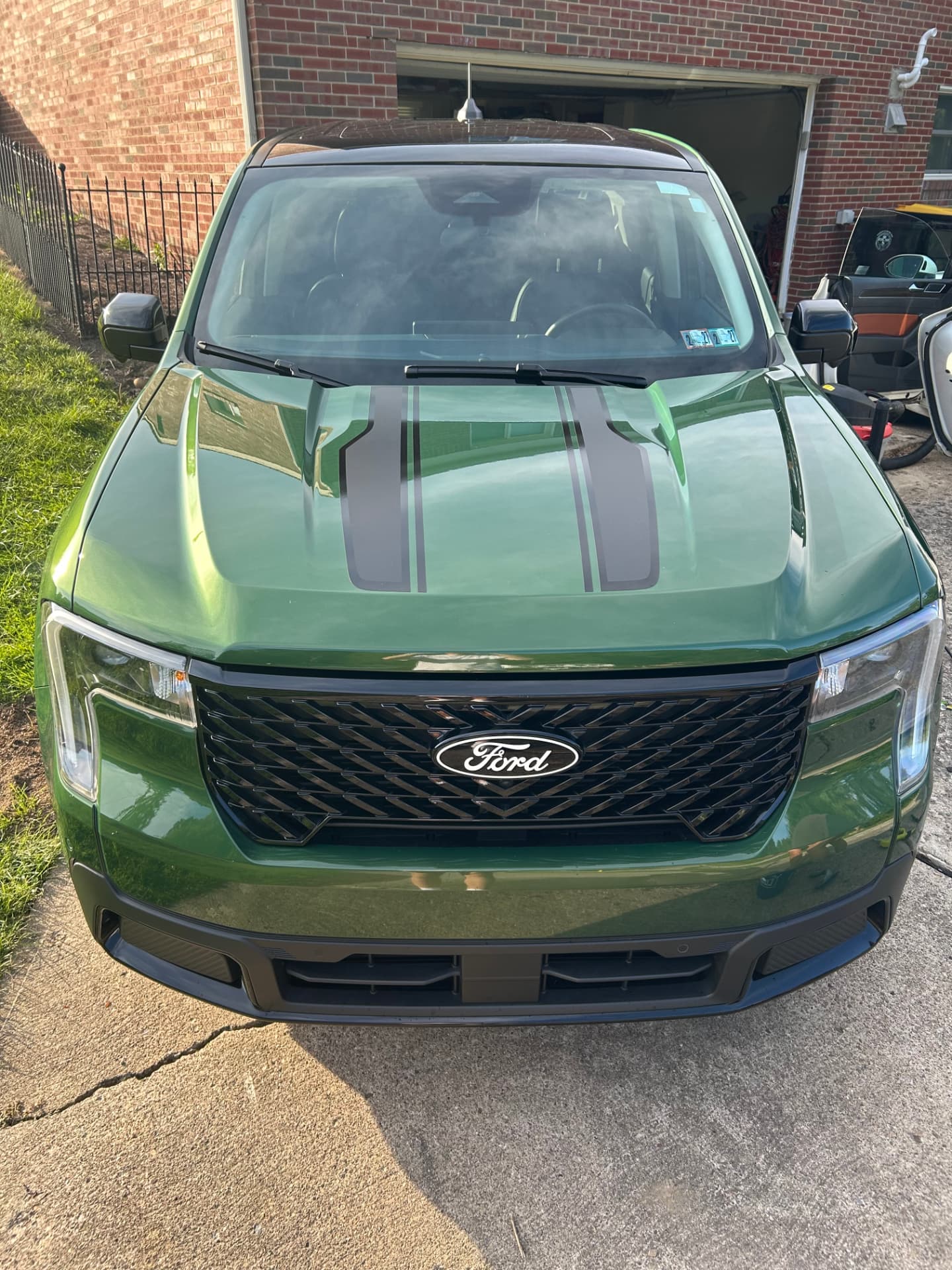Green Ford Maverick with black hood stripes, front view