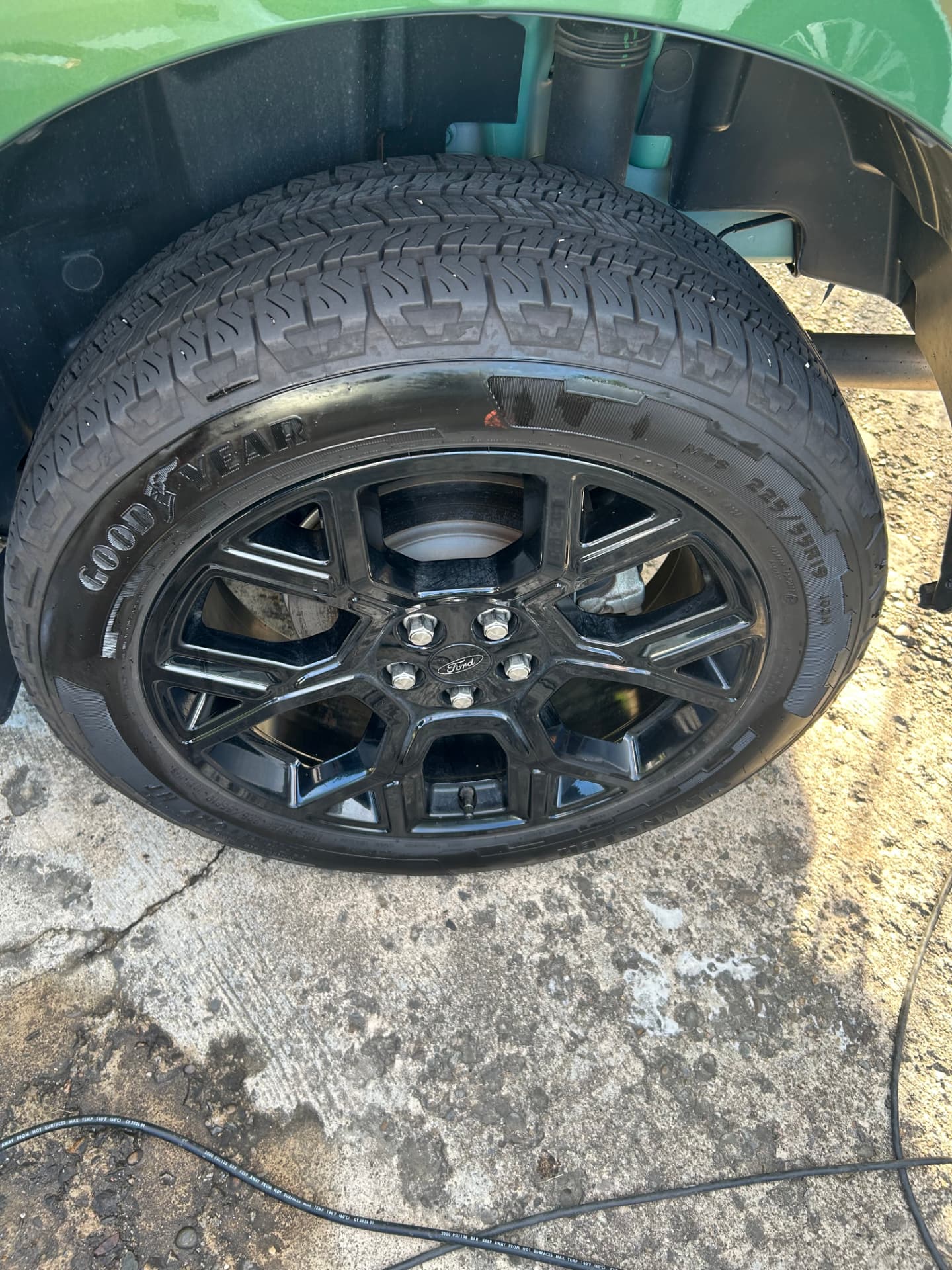 Gloss black wheel and tire on a green Ford Maverick